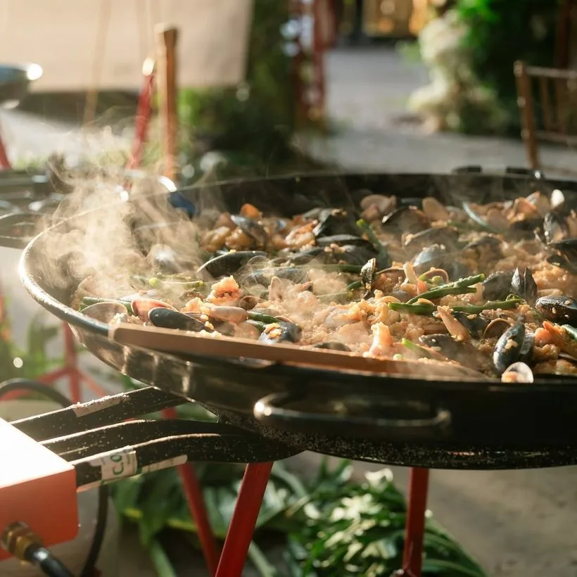 Seafood paella cooking on site in a wide pan